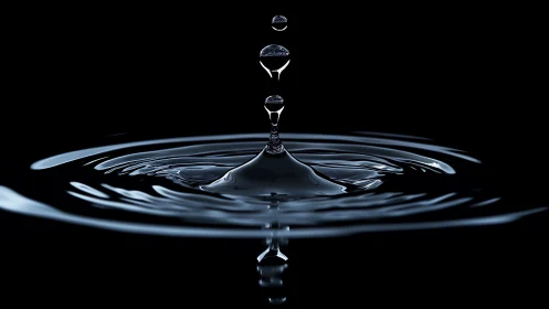 Minimalist water droplet splash over reflective black pool.