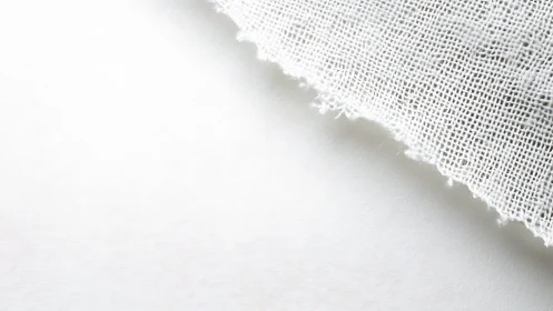 Whispering linen edge drifting across a white hush field.