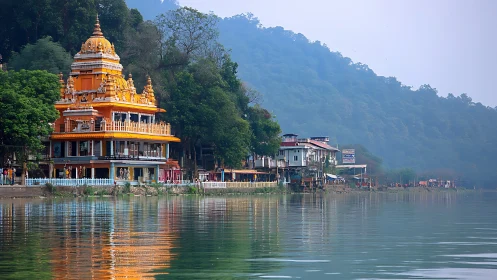 Lakeside temple glow beside misty green hillside reflections.