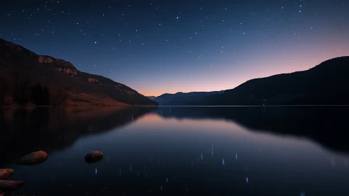 Still mountain lake under stars at deep blue twilight.