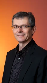 Confident professional portrait against glowing orange backdrop.