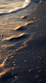 Footprints fading in golden surf along twilight shoreline.