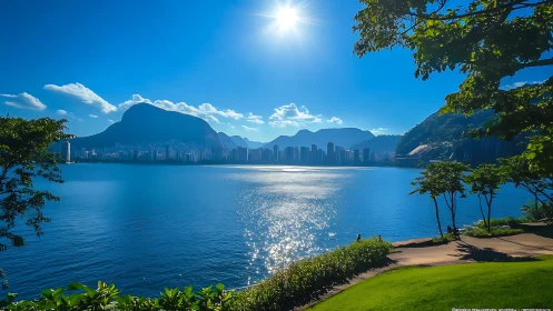 Sunlit urban bay with mountains, skyline, and waterfront park.