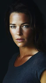 Studio portrait of woman in dark shirt against black backdrop.