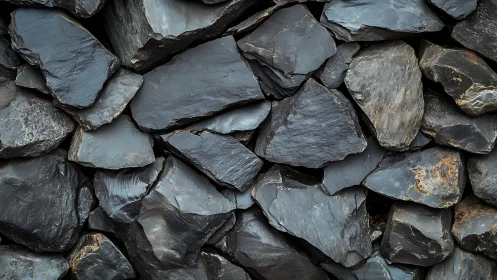 Dark slate rock wall texture with rough angular stones.