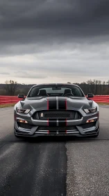 Bold gray sports car waits on track under heavy storm clouds
