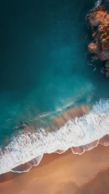 Vertical aerial photograph shows shoreline, surf and rocky cliff
