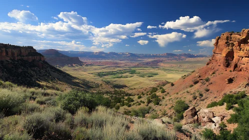 Sunlit red canyon opening toward distant fertile valley plains.