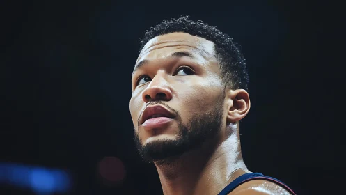 Basketball player looks upward under bright arena lighting