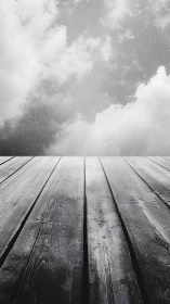 Grayscale timber deck receding into diffuse atmospheric cloudfield.
