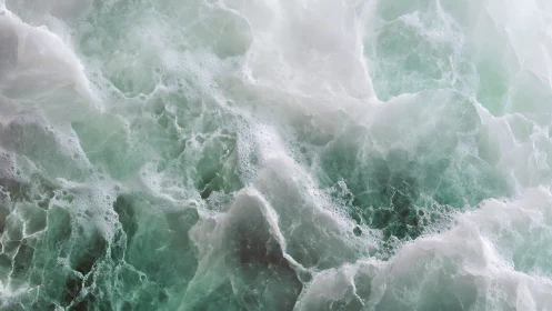 Gentle sea foam swirls across soft green ocean waves