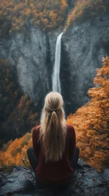 Solitary hiker observing distant waterfall in autumn gorge.