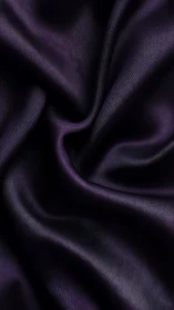 Close-up of folded dark purple satin textile surface.