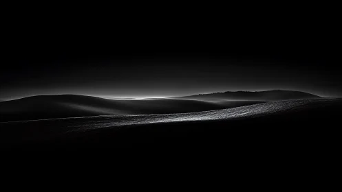 Monochrome undulating dunes under low horizon light.