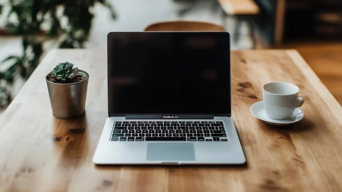 Cozy wooden desk with laptop, coffee cup, and small plant.
