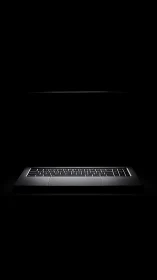Backlit laptop keyboard glows inside dark minimalist frame.