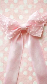 Pink satin bow on pale polka dot textile background.