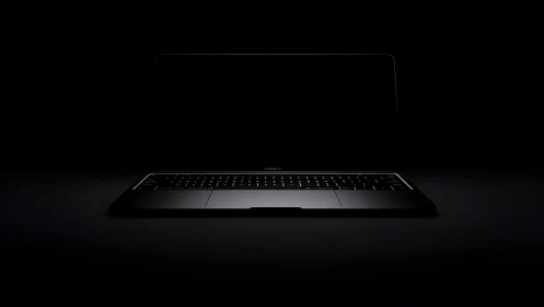 Backlit laptop keyboard emerges from deep negative space