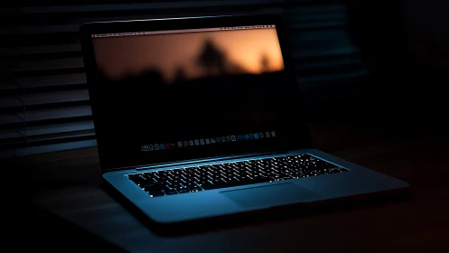 Backlit laptop in low key office lighting with bokeh screen.