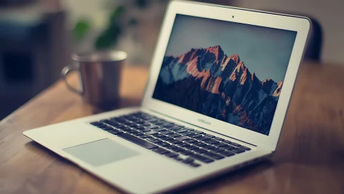 Slim laptop displays sunlit mountain wallpaper on desk