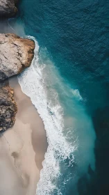 Aerial coastal interface of granite cliffs and littoral surf.