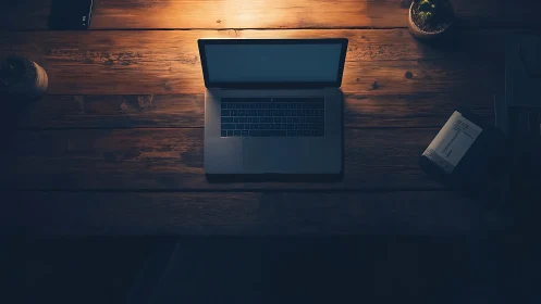 Overhead view shows open laptop on wooden desk at night