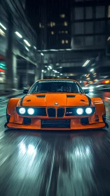 Widebody orange BMW race car at speed on wet neon city street