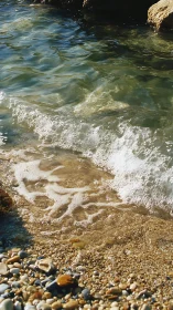 Shallow coastal wave breaking over pebbled shoreline detail