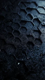 Hexagonal voids on dark industrial surface in shadow.