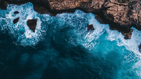 Aerial surf crashes along rugged sunlit coastal cliffs.