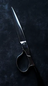Stainless steel scissors on textured dark studio background.