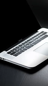 Quiet laptop corner invites focus on sleek dark desk.