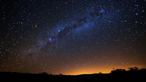 Midnight star river arches above an ember-lit horizon sky.