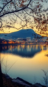 Urban riverfront at dusk with mountain and reflected lights.