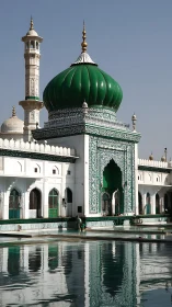 Green-domed mosque reflects over still courtyard pool