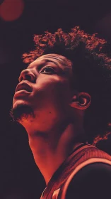 Upward-lit basketball portrait in dramatic orange glow.