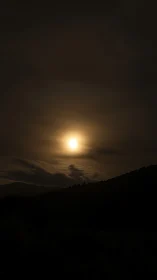 Moonlit haze settles softly above dark rolling hills.