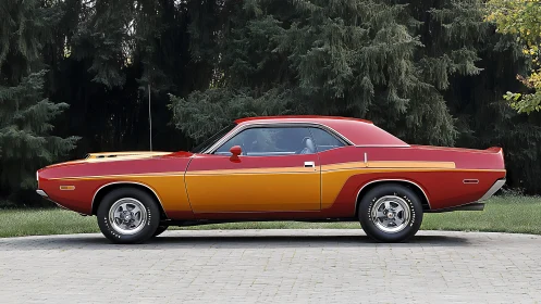 Classic red and orange muscle car parked by tall trees.