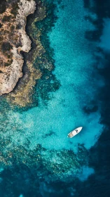 Drone top view of small motorboat over shallow turquoise reef.
