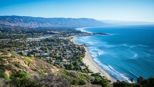 Sunny coastal town stretching along a calm blue shoreline.