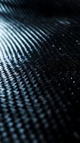 Curved carbon fiber surface with reflective woven texture pattern.