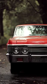 Classic red muscle car gleams against a moody forest backdrop.