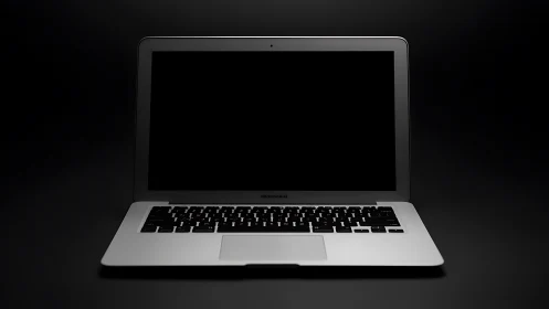 Sleek silver laptop waits quietly with its dark screen aglow