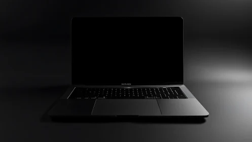 Sleek black laptop centered on dark reflective surface.