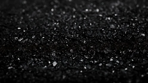 Wet black asphalt macro texture with glistening granules.