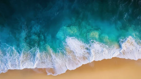 Turquoise surf curls over golden sand in aerial seascape.