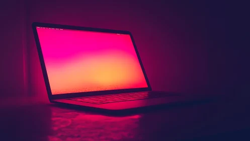 Open laptop with gradient screen in dark low light scene.