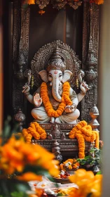 Ganesha idol in ornate silver shrine with marigold garlands.