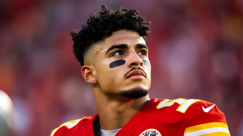 Professional football player in red uniform on sideline field.