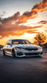 Lowered silver sedan stands on empty road at vivid sunset